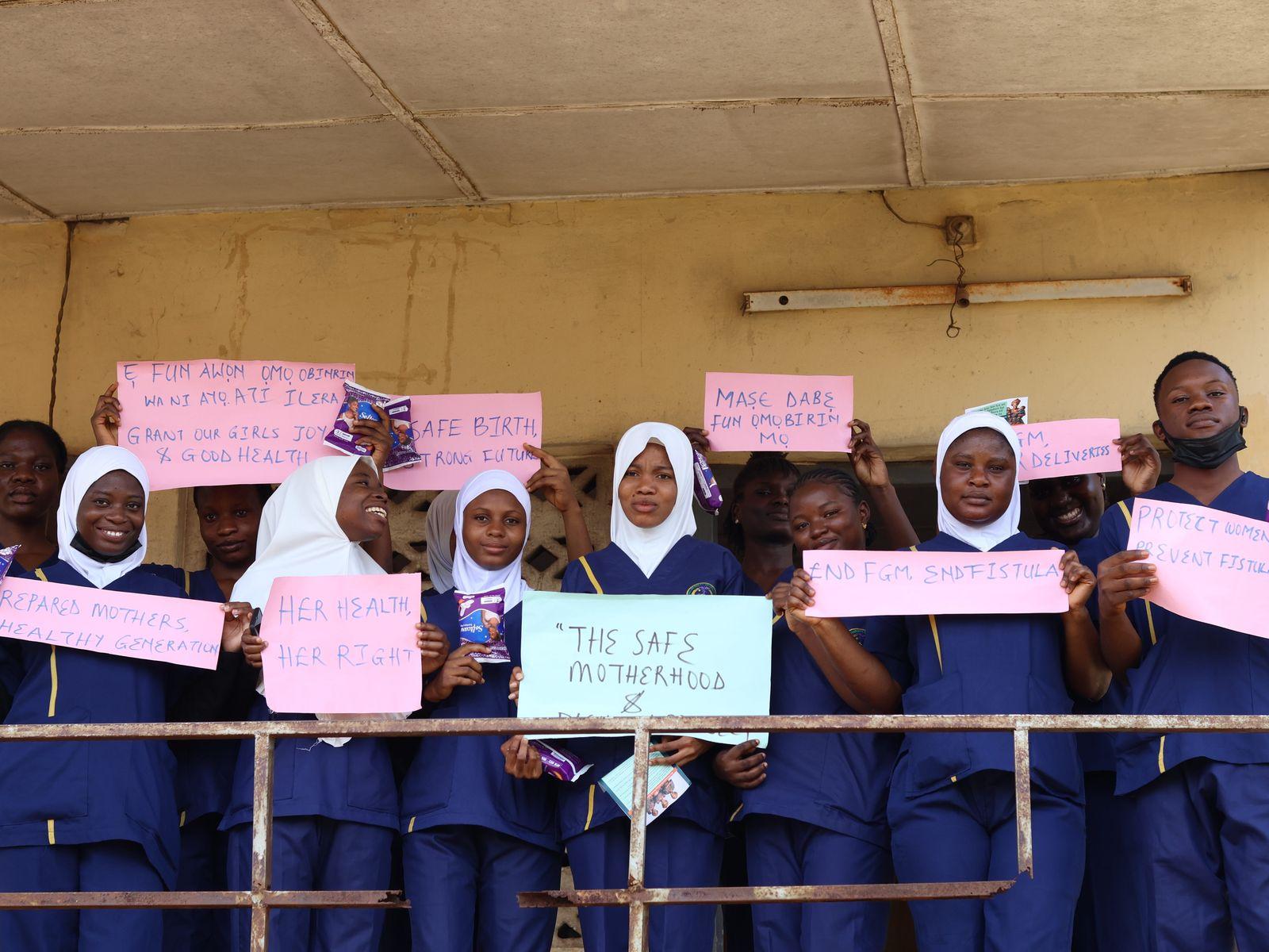 Student nurses hold signs for safe motherhood and an end to FGM and fistula